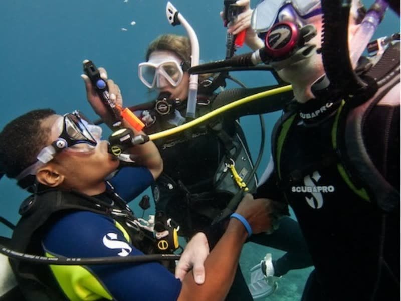 Tauchlehrer mit zwei Kursteilnehmern unter Wasser